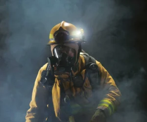 Feuerwehrmann mit Komplettausrüstung und Helmlampe bzw. Stirnlampe in dichtem Rauch